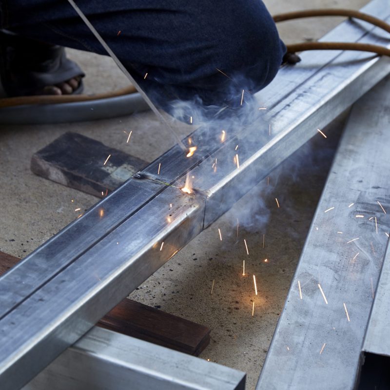 Asian man worker making sparks while welding steel